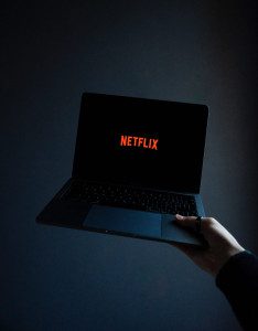 A laptop is held with the Netflix logo on the screen