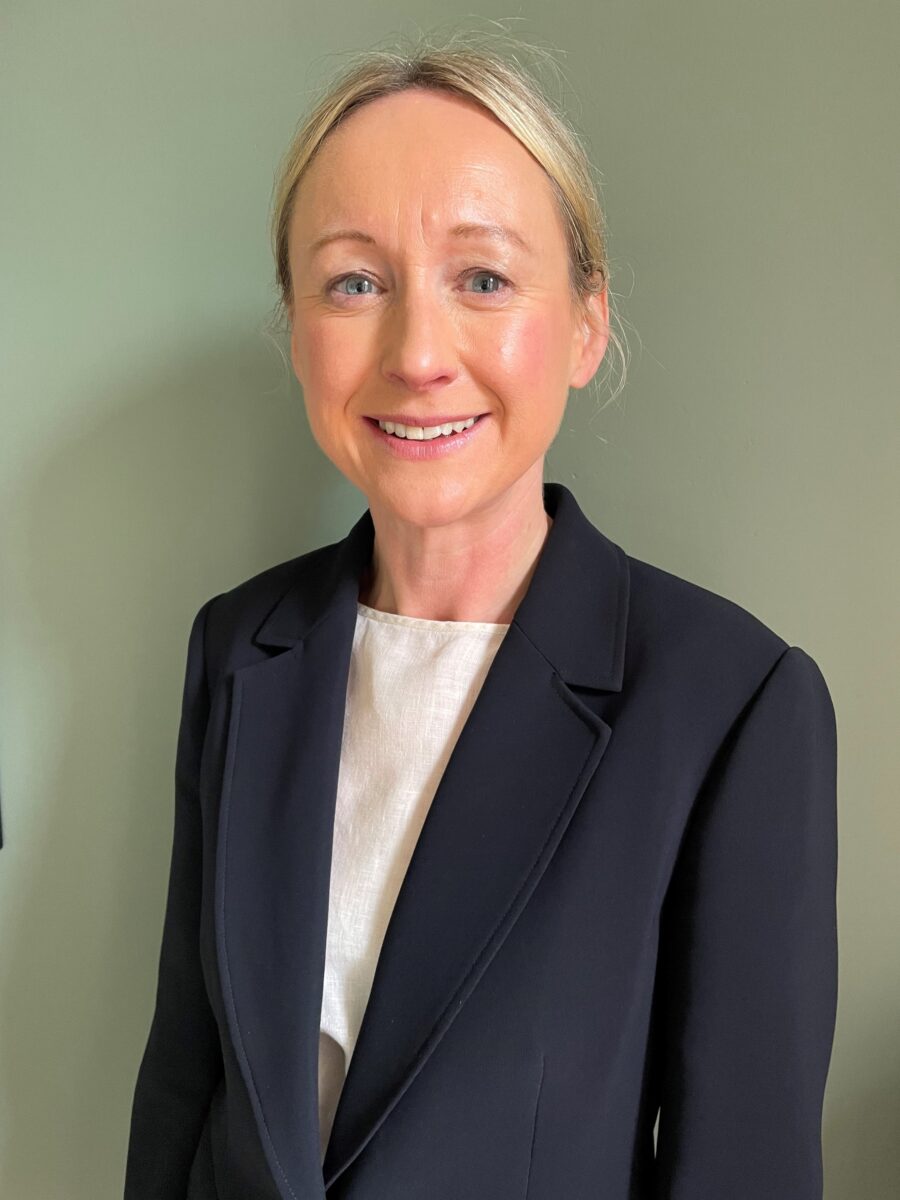 Professional headshot of Gillian Booth, she is wearing a black blazer and smiling. 