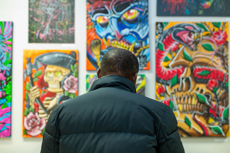 a person looking at artworks on a wall in an exhibition