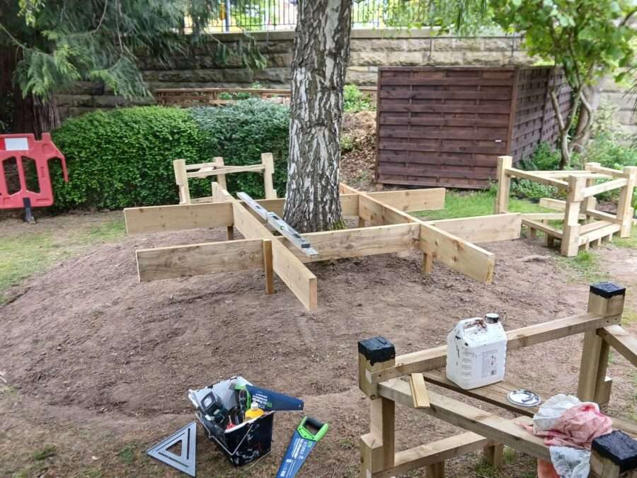 A wooden platform in-construction around a tree 