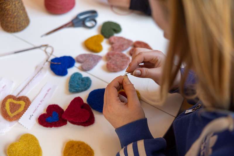 A crafting group: close-up of a woman's hands while she stitches felt hearts